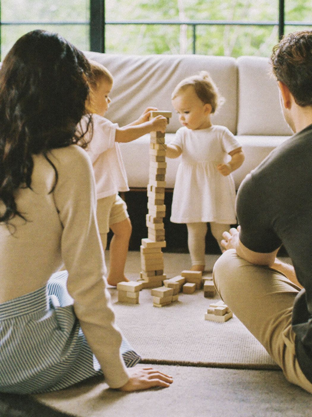 Parents watching toddlers build with wooden blocks