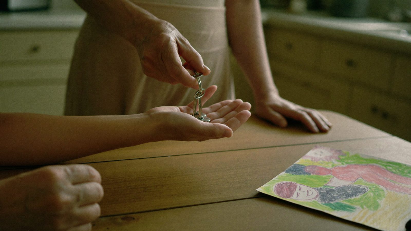 A hand passing keys to a child's palm